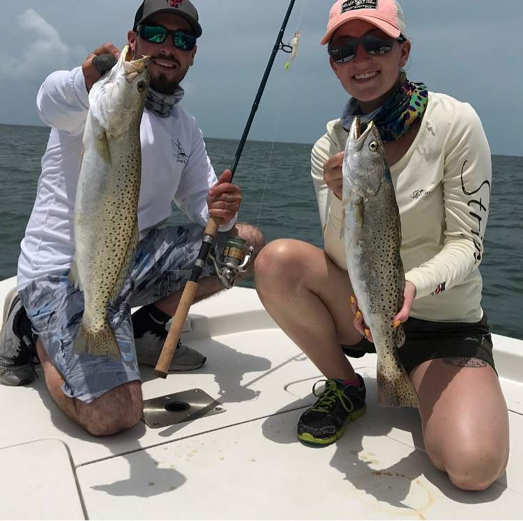 Man and woman holding up speckled trout