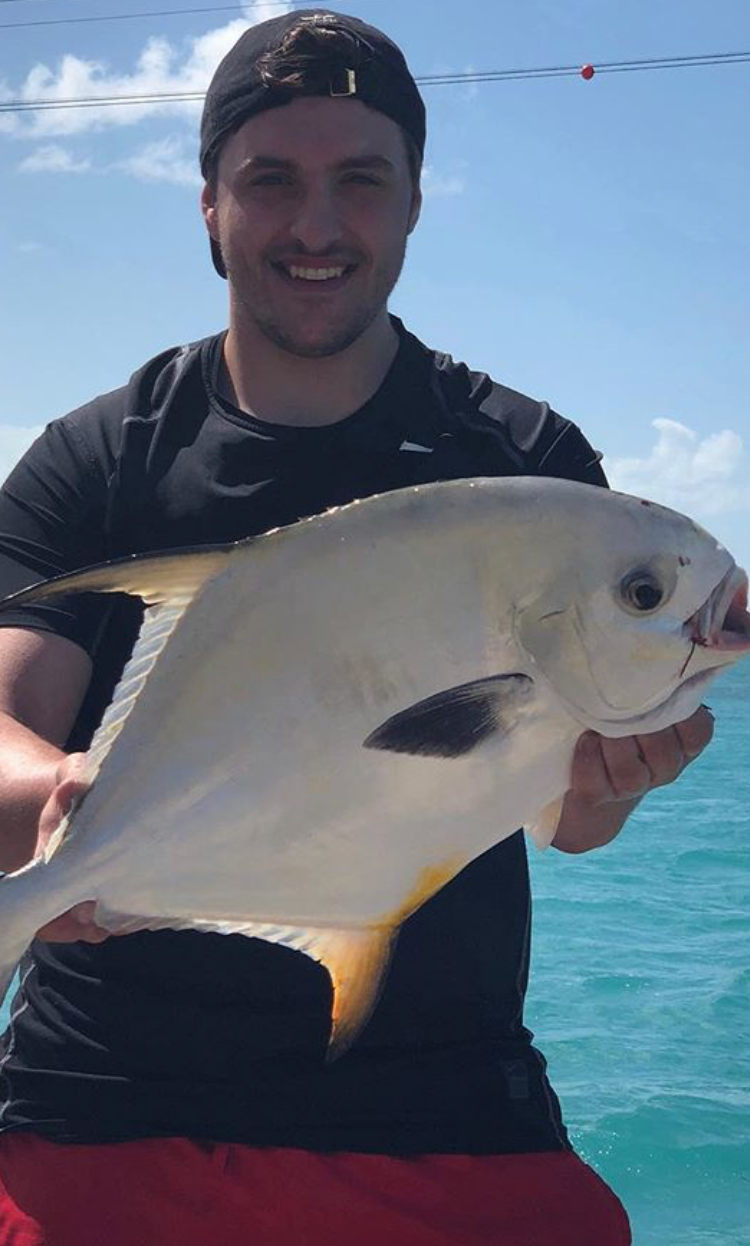 Man holding white and yellow permit fish