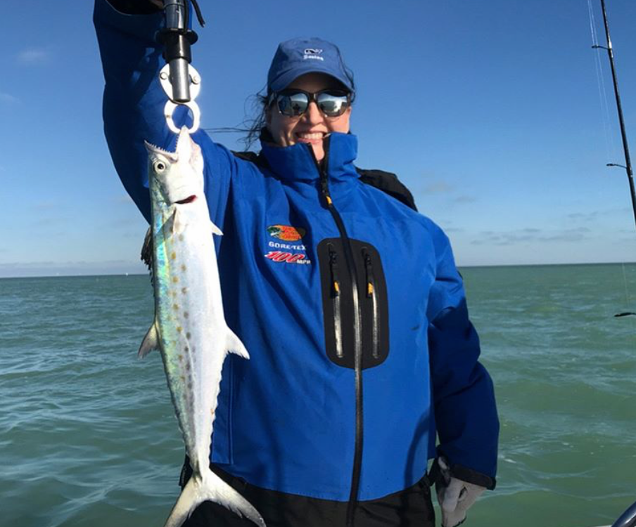 Woman smiling in jacket holding spanish mackerel